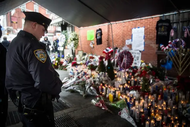 A police officer pays his respect at the memorial site for Rafael Ramos and Wenjian Liu in Bed-Stuy